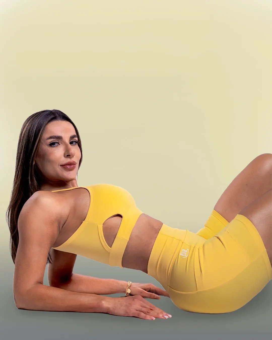 Modelo deitada com conjunto fitness amarelo da Evolua